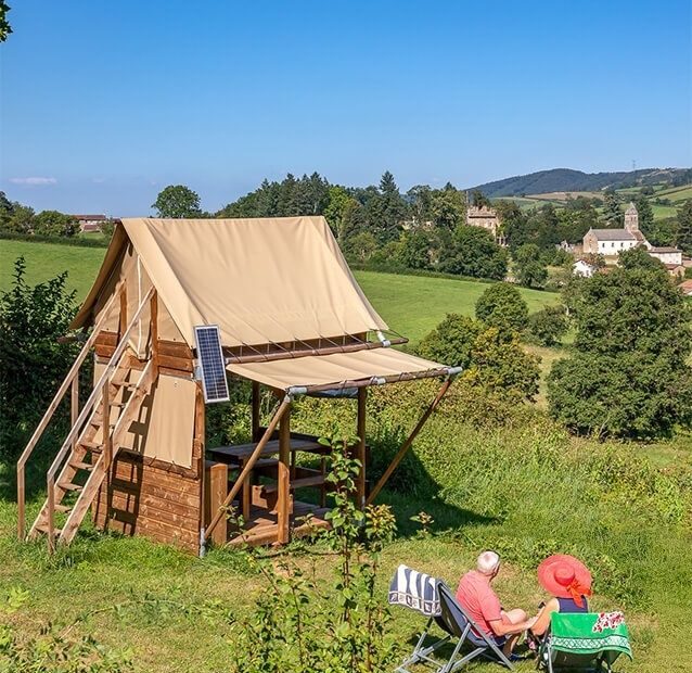 Bivouac aménagé avec tente en bois dans une campagne vallonnée