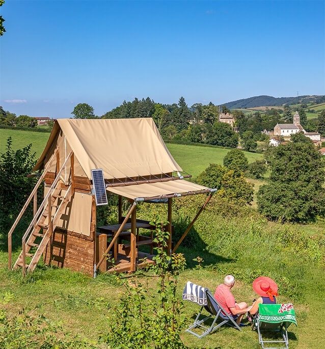 Bivouac aménagé avec tente en bois dans une campagne vallonnée